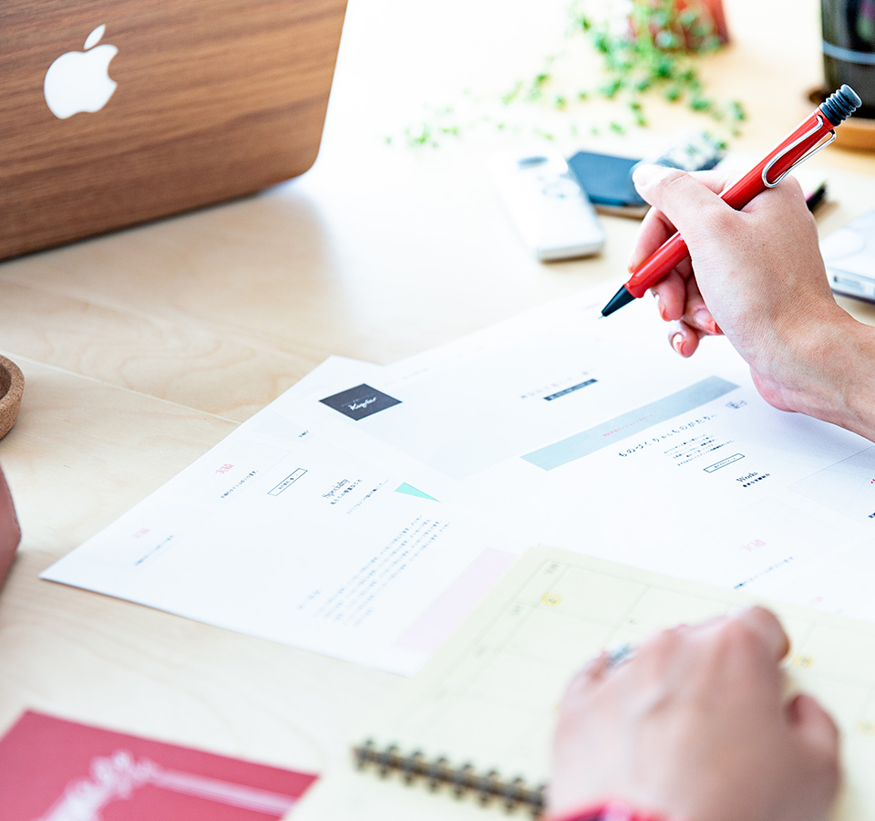 書類を赤ペンでチェックしている手元